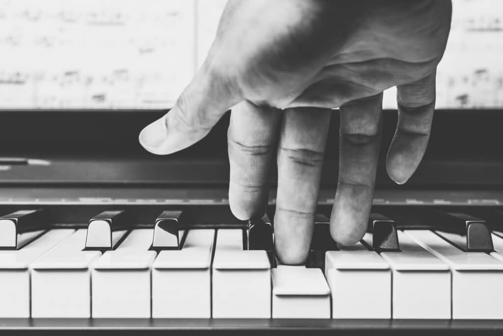 Mains Jouant du Piano : Clavier en Gros Plan Gros plan en noir et blanc sur des doigts jouant du piano, action de presser les touches blanches.