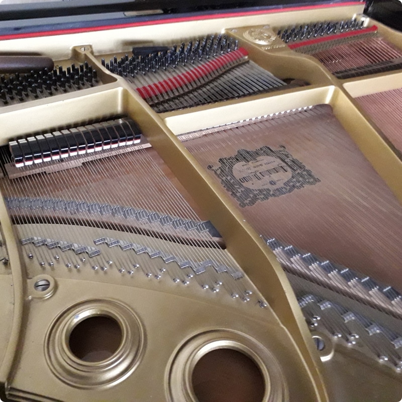 Piano à queue Hardman Peck New York : Intérieur détaillé Intérieur de piano à queue : cadre doré, cordes tendues, étouffoirs et "HARDMAN, PECK & CO. NEW YORK" sur la table d'harmonie.
