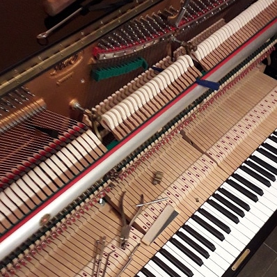 Réparation de piano : Découvrez le mécanisme interne Mécanisme interne de piano à queue ouvert : cordes, marteaux, étouffoirs. Outils de réparation ou d'accordage sont posés sur l'action et le clavier.